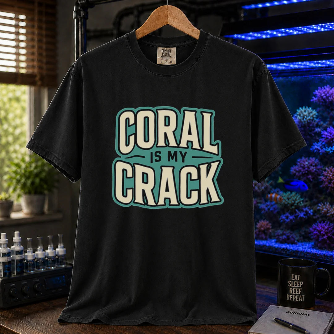 Saltwater aquarium graphic t-shirt featuring bold retro typography reading Coral Is My Crack in cream and black with a teal background accent, black crew neck tee