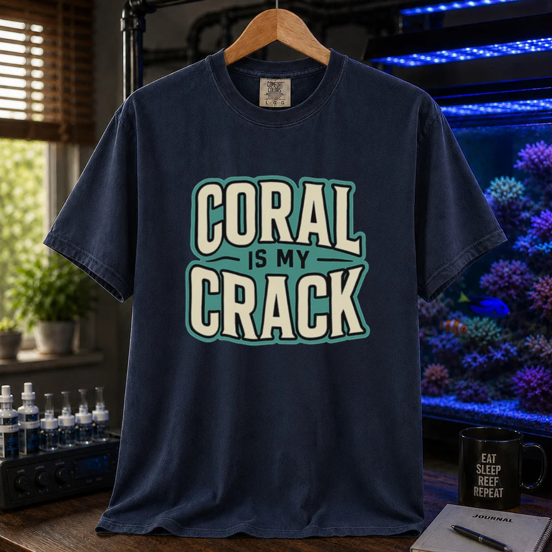 Saltwater aquarium graphic t-shirt featuring bold retro typography reading Coral Is My Crack in cream and black with a teal background accent, navy crew neck tee