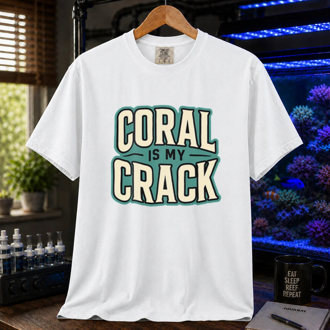 Saltwater aquarium graphic t-shirt featuring bold retro typography reading Coral Is My Crack in cream and black with a teal background accent, white crew neck tee