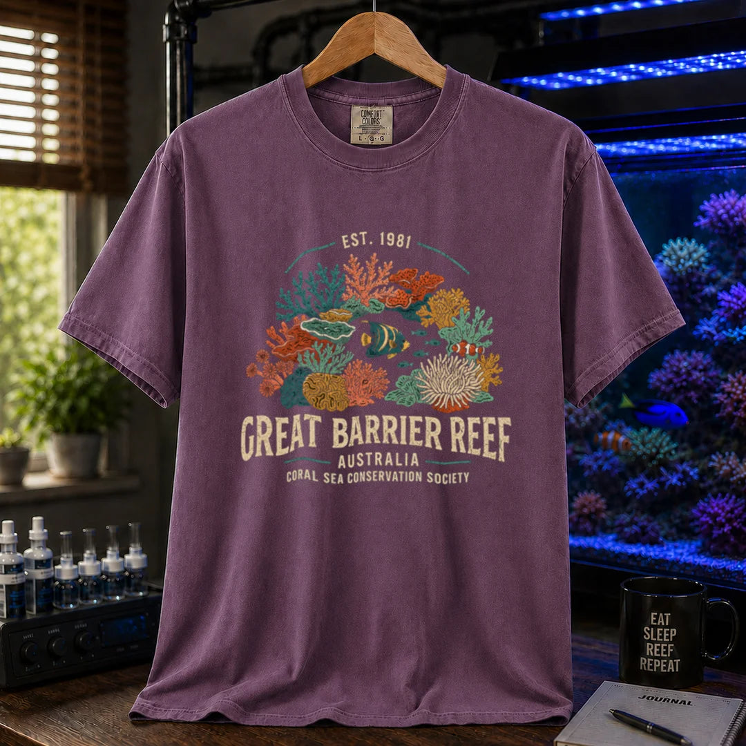 Saltwater aquarium graphic t-shirt featuring detailed vintage illustration of coral reefs and tropical fish with text reading Great Barrier Reef Australia Coral Sea Conservation Society Est. 1981, purple crew neck tee