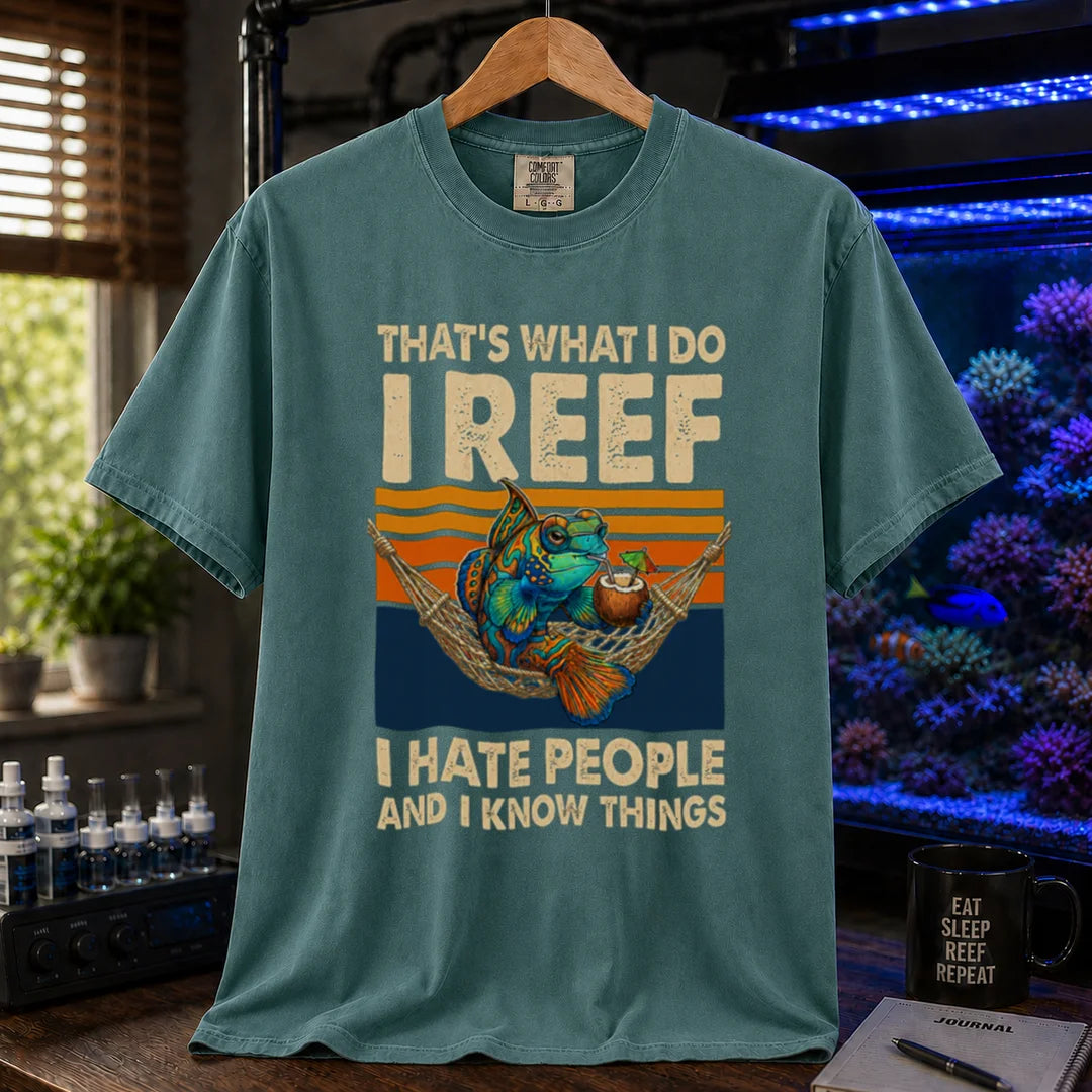 Saltwater aquarium graphic t-shirt featuring a mandarin goby in a hammock with a drink against a retro sunset and text reading That's What I Do I Reef I Hate People And I Know Things, green crew neck tee
