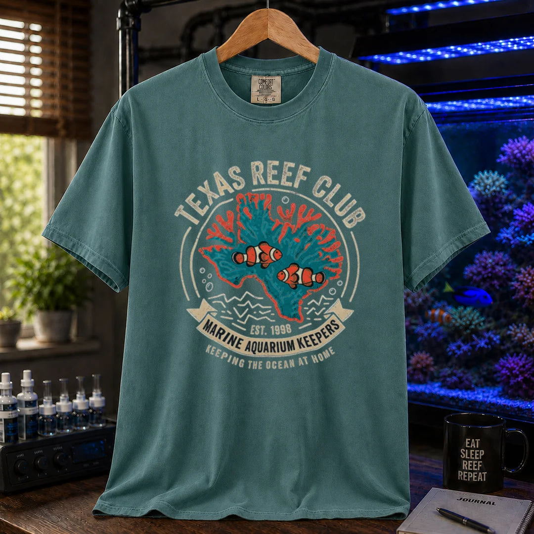 Saltwater aquarium graphic t-shirt featuring a vintage emblem with coral shaped like Texas, clownfish, and text reading Texas Reef Club Marine Aquarium Keepers Est. 1998, green crew neck tee