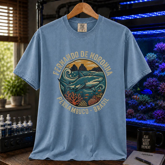 Saltwater aquarium graphic t-shirt featuring a retro circular emblem with a shark and coral, arched text reading Fernando de Noronha Pernambuco Brasil, blue crew neck tee
