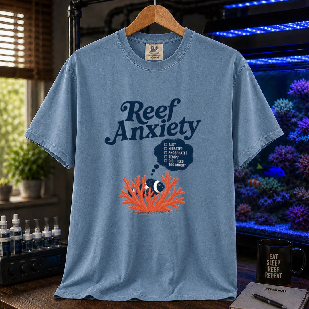 Saltwater aquarium graphic t-shirt featuring blue text reading Reef Anxiety and an illustration of a clownfish in coral with a thought bubble checklist, blue crew neck tee