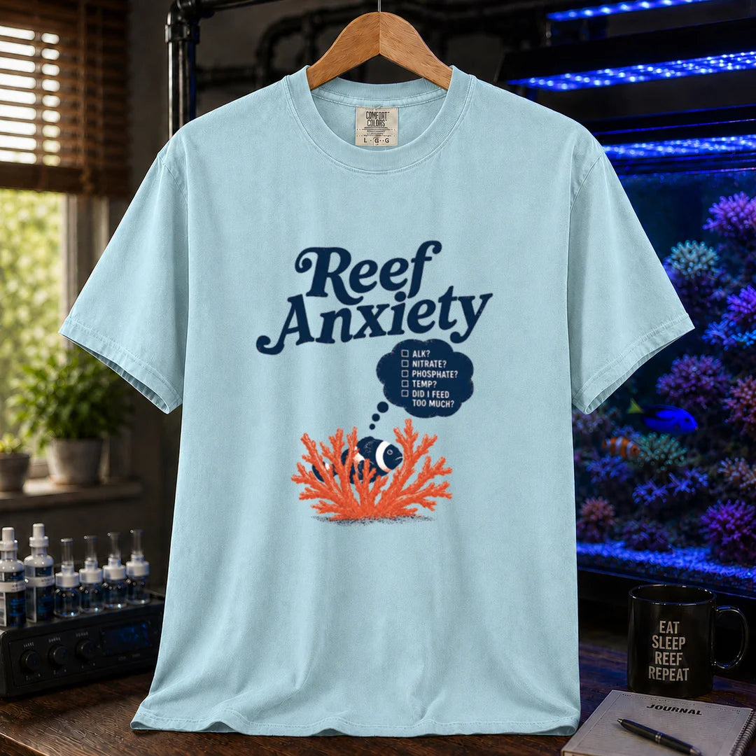Saltwater aquarium graphic t-shirt featuring blue text reading Reef Anxiety and an illustration of a clownfish in coral with a thought bubble checklist, light blue crew neck tee