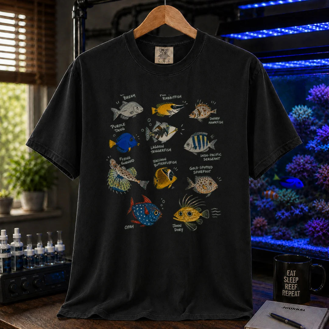 Saltwater aquarium graphic t-shirt design featuring a vintage marine species field guide layout with labeled illustrations of various fish including a Purple Tang, Lagoon Triggerfish, and Flying Gurnard, black crew neck tee