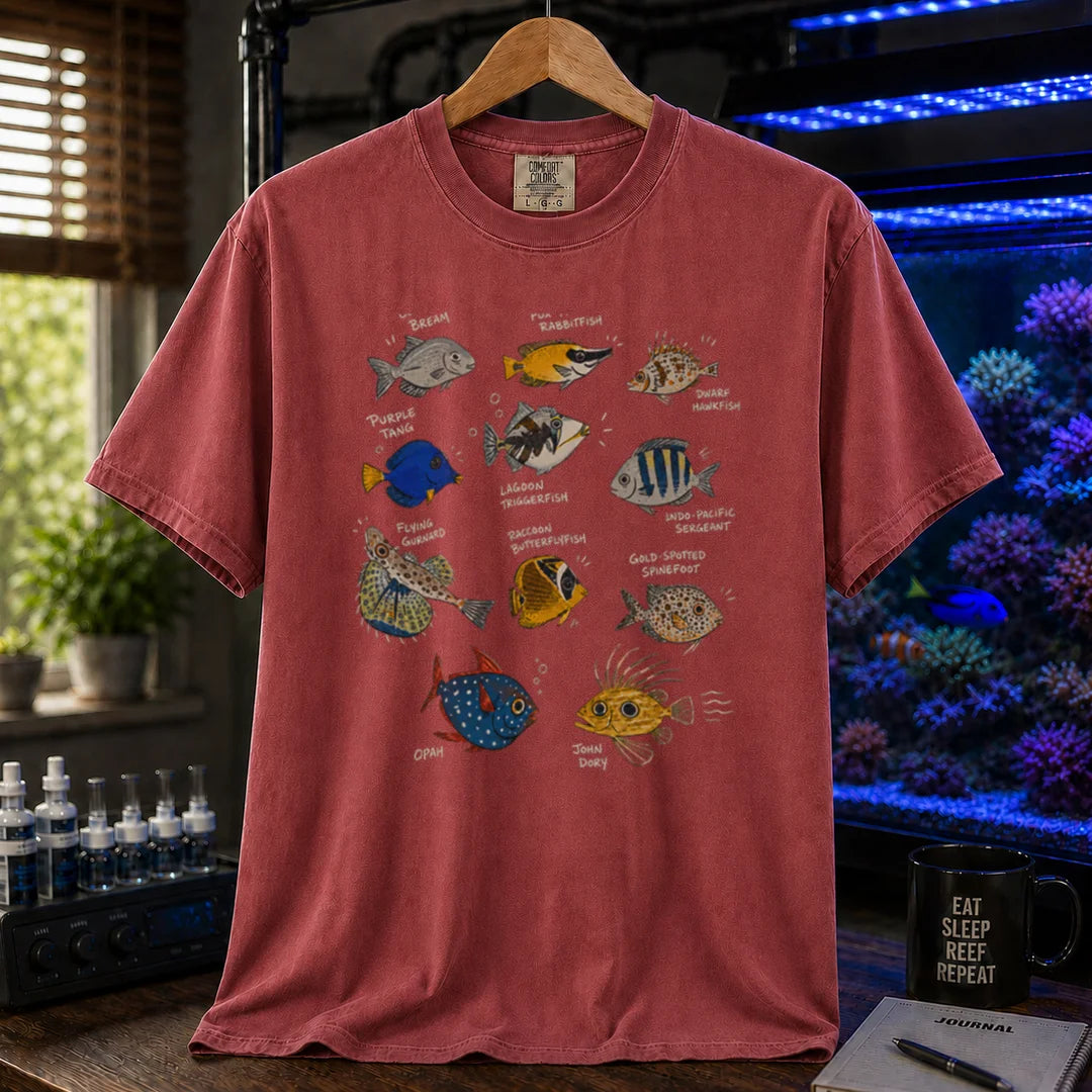 Saltwater aquarium graphic t-shirt design featuring a vintage marine species field guide layout with labeled illustrations of various fish including a Purple Tang, Lagoon Triggerfish, and Flying Gurnard, maroon, red crew neck tee