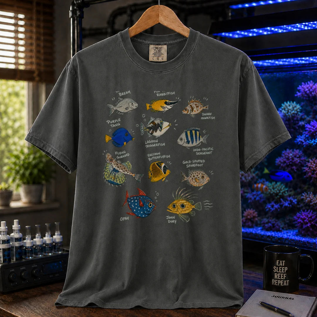 Saltwater aquarium graphic t-shirt design featuring a vintage marine species field guide layout with labeled illustrations of various fish including a Purple Tang, Lagoon Triggerfish, and Flying Gurnard, dark grey crew neck tee