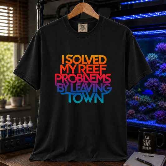Saltwater aquarium graphic t-shirt featuring bold stacked gradient typography reading I Solved My Reef Problems By Leaving Town, black crew neck tee