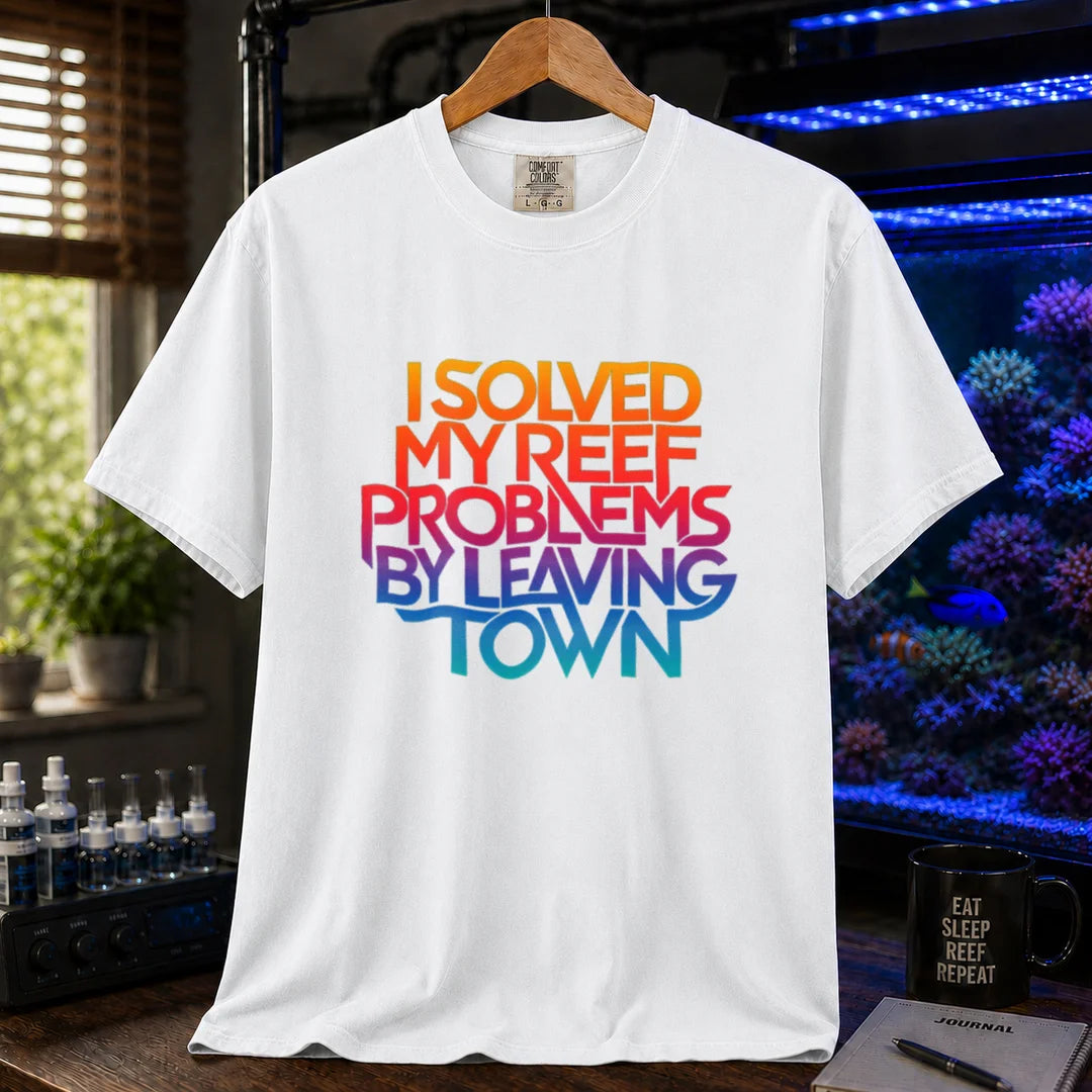 Saltwater aquarium graphic t-shirt featuring bold stacked gradient typography reading I Solved My Reef Problems By Leaving Town, white crew neck tee
