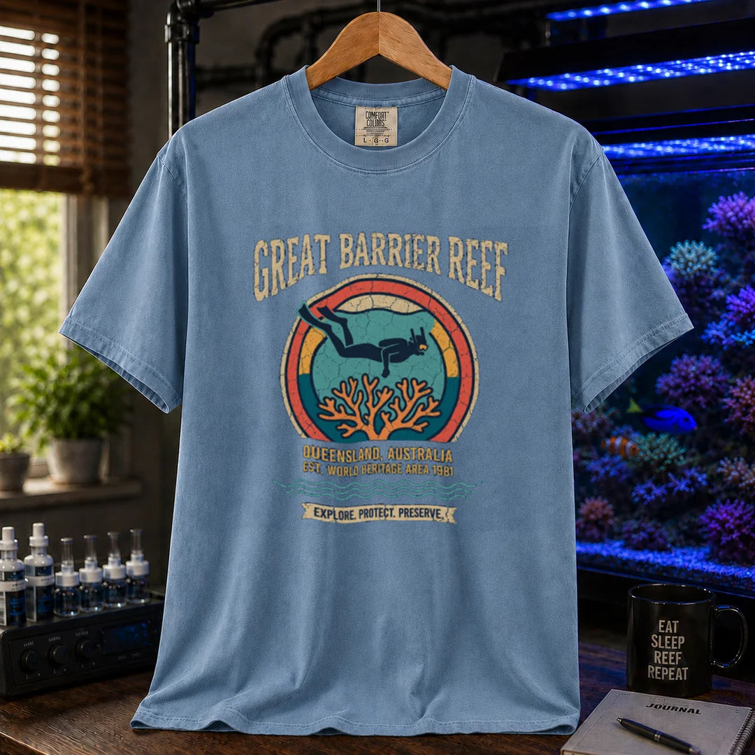 Saltwater aquarium graphic t-shirt featuring a retro circular emblem with a scuba diver and coral, arched text reading Great Barrier Reef Queensland Australia Est World Heritage Area 1981, blue crew neck tee