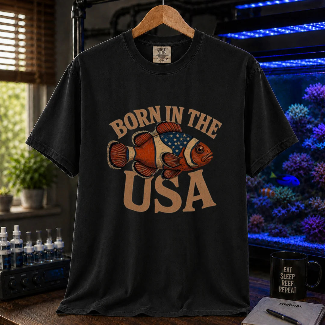 Saltwater aquarium graphic t-shirt featuring distressed vintage typography reading Born in the USA with an illustrated clownfish patterned like the American flag, black crew neck tee