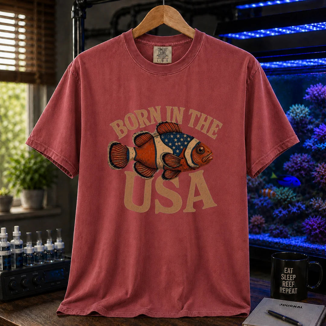 Saltwater aquarium graphic t-shirt featuring distressed vintage typography reading Born in the USA with an illustrated clownfish patterned like the American flag, maroon, red crew neck tee