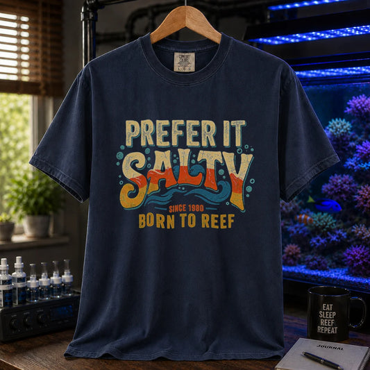 Saltwater aquarium graphic t-shirt featuring distressed retro typography in yellow, orange, and teal reading Prefer It Salty Born To Reef Since 1980 with wave graphics, navy crew neck tee