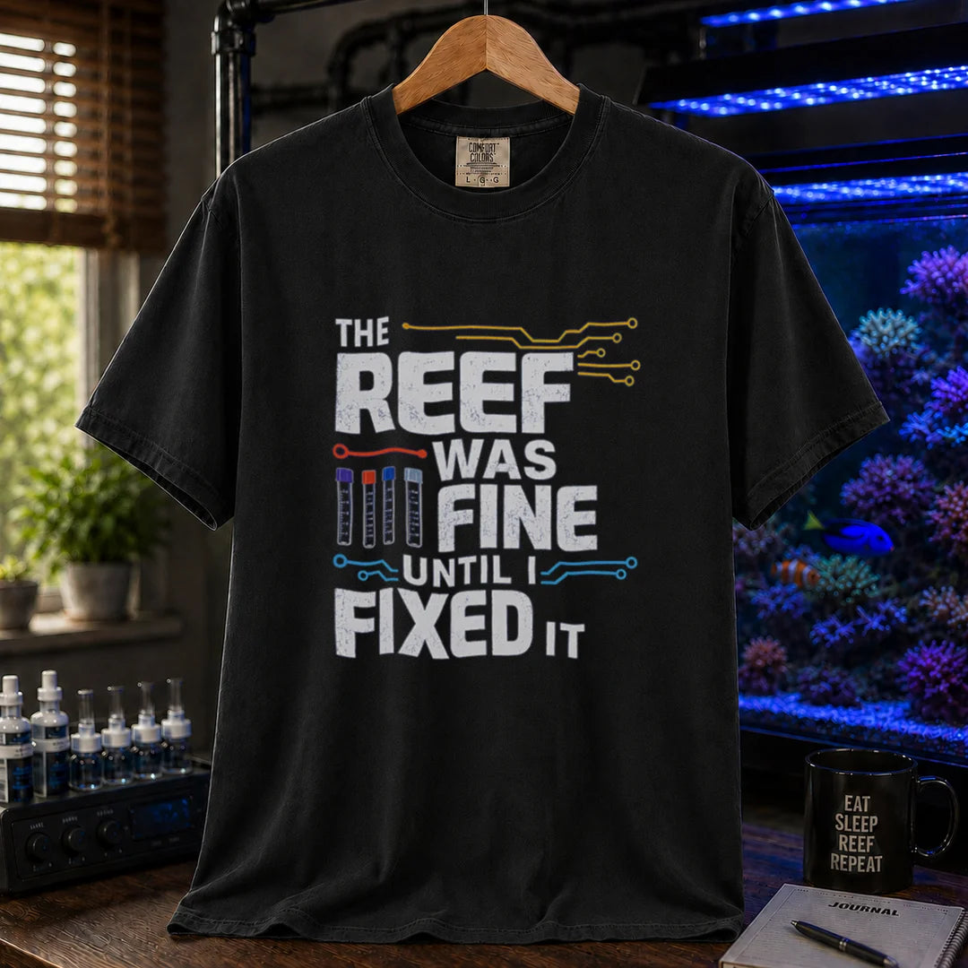 Saltwater aquarium graphic t-shirt featuring distressed white typography reading The Reef Was Fine Until I Fixed It with test vial icons and circuit lines, black crew neck tee