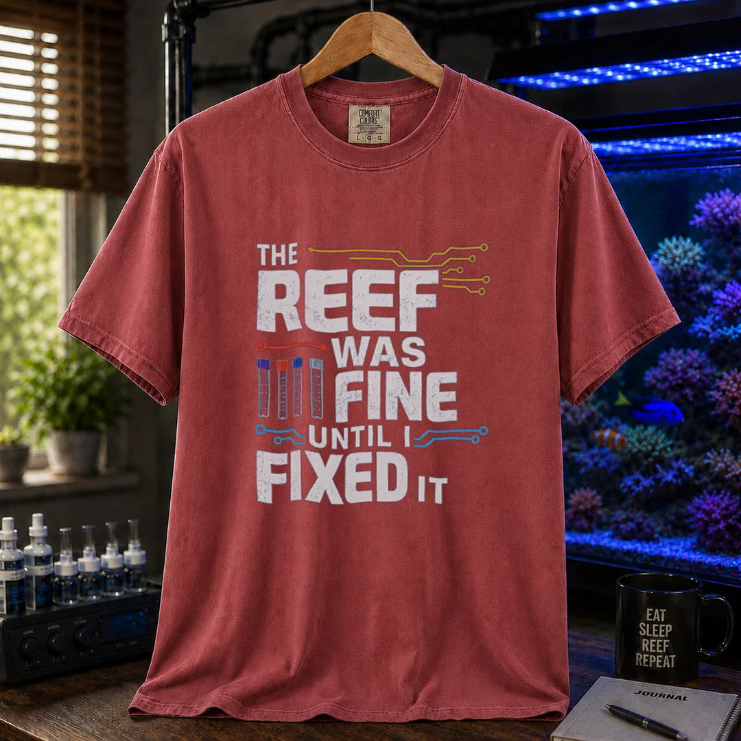 Saltwater aquarium graphic t-shirt featuring distressed white typography reading The Reef Was Fine Until I Fixed It with test vial icons and circuit lines, maroon, red crew neck tee