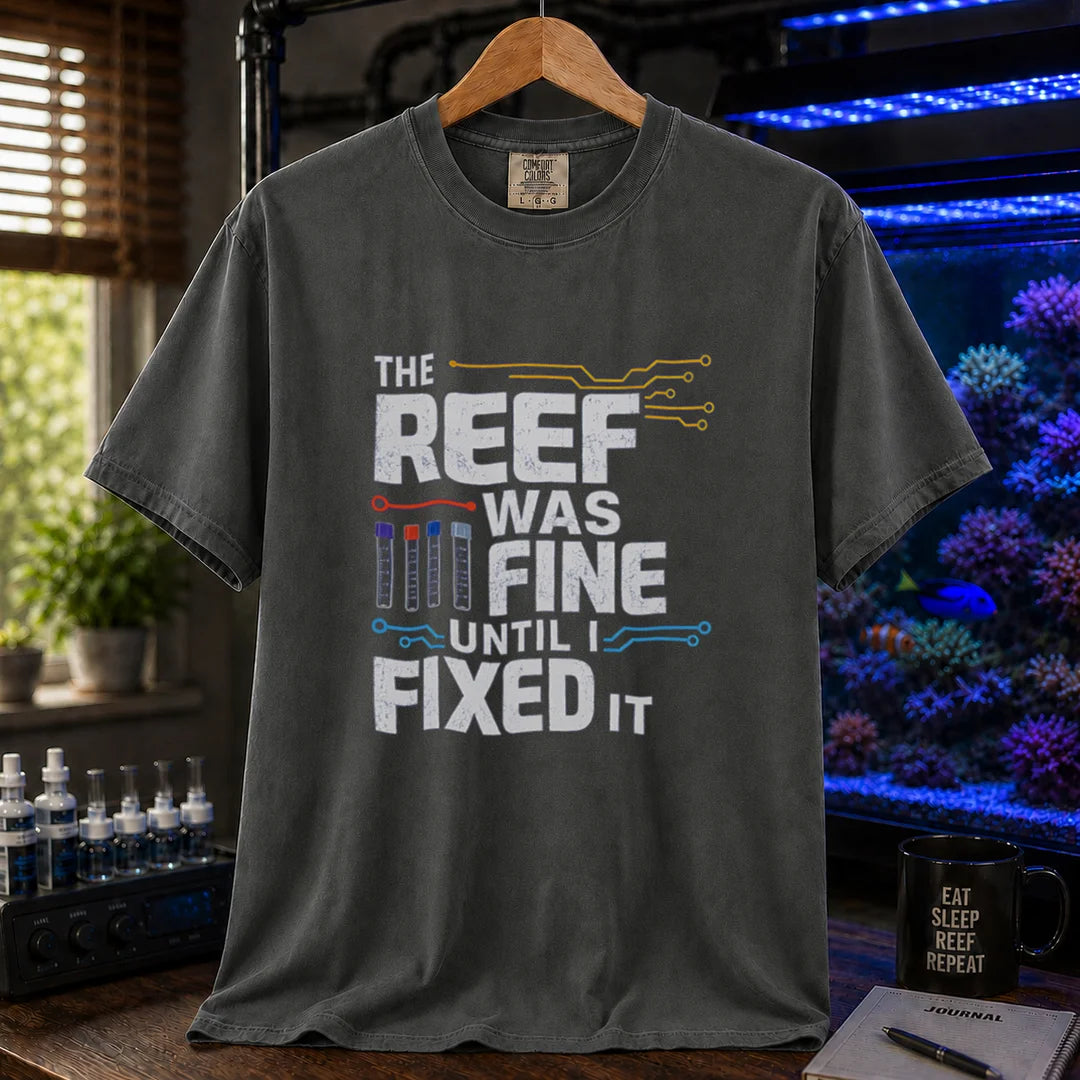 Saltwater aquarium graphic t-shirt featuring distressed white typography reading The Reef Was Fine Until I Fixed It with test vial icons and circuit lines, dark grey crew neck tee