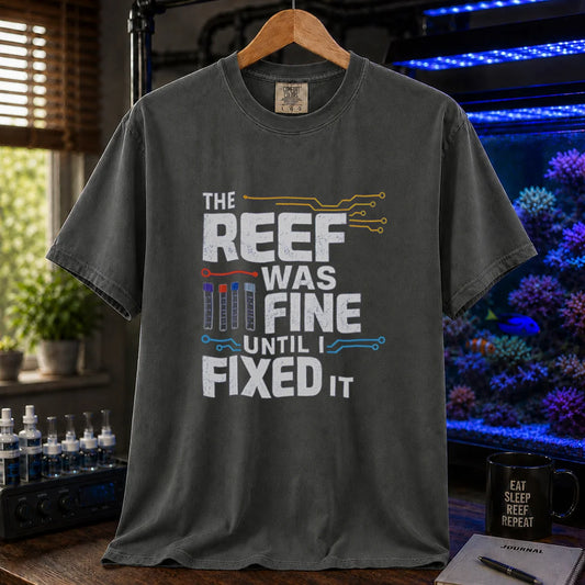 Saltwater aquarium graphic t-shirt featuring distressed white typography reading The Reef Was Fine Until I Fixed It with test vial icons and circuit lines, dark grey crew neck tee