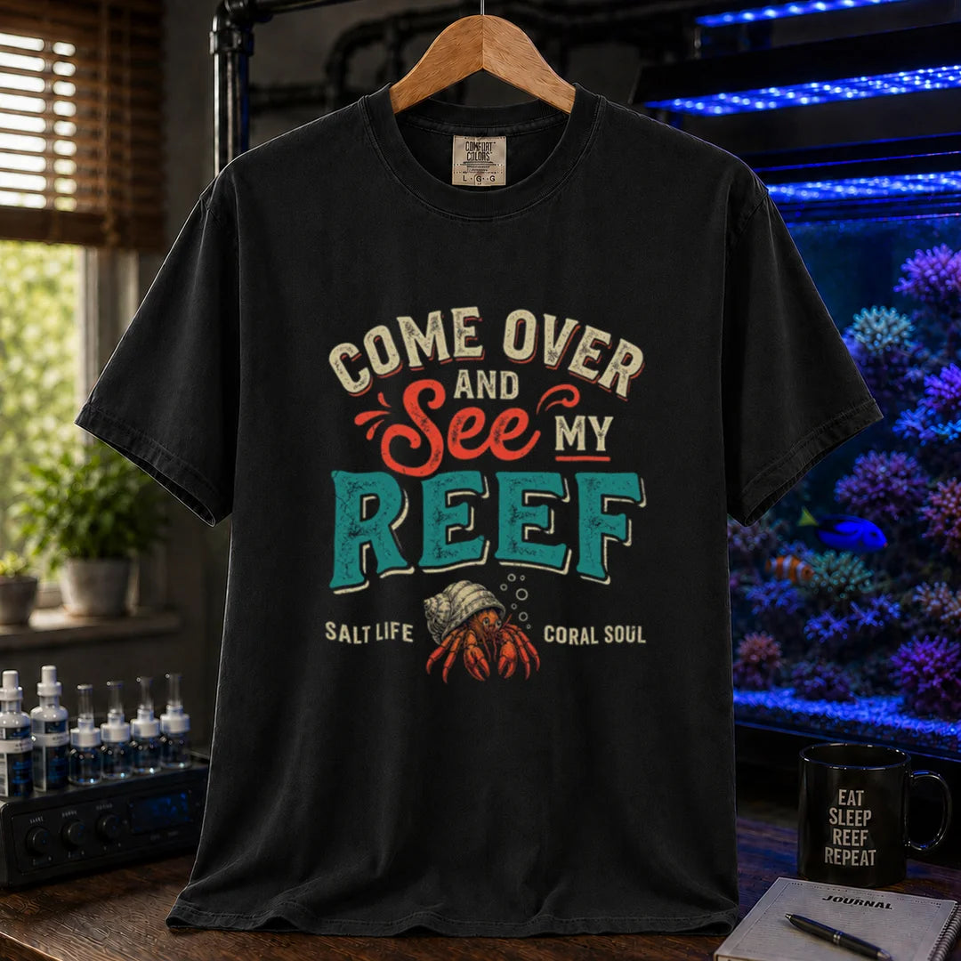 Saltwater aquarium graphic t-shirt featuring distressed retro typography reading Come Over And See My Reef with a hermit crab illustration and footer text, black crew neck tee
