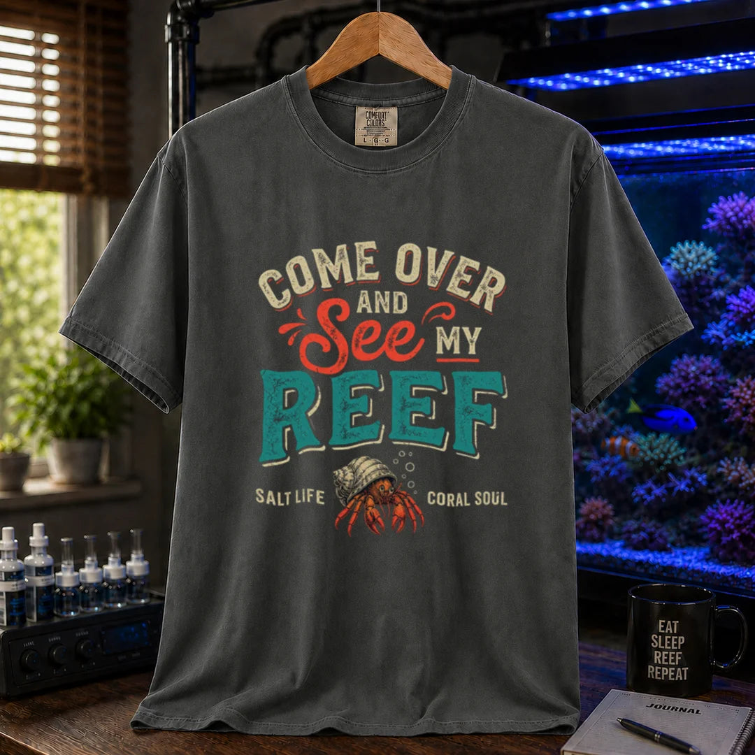 Saltwater aquarium graphic t-shirt featuring distressed retro typography reading Come Over And See My Reef with a hermit crab illustration and footer text, dark grey crew neck tee
