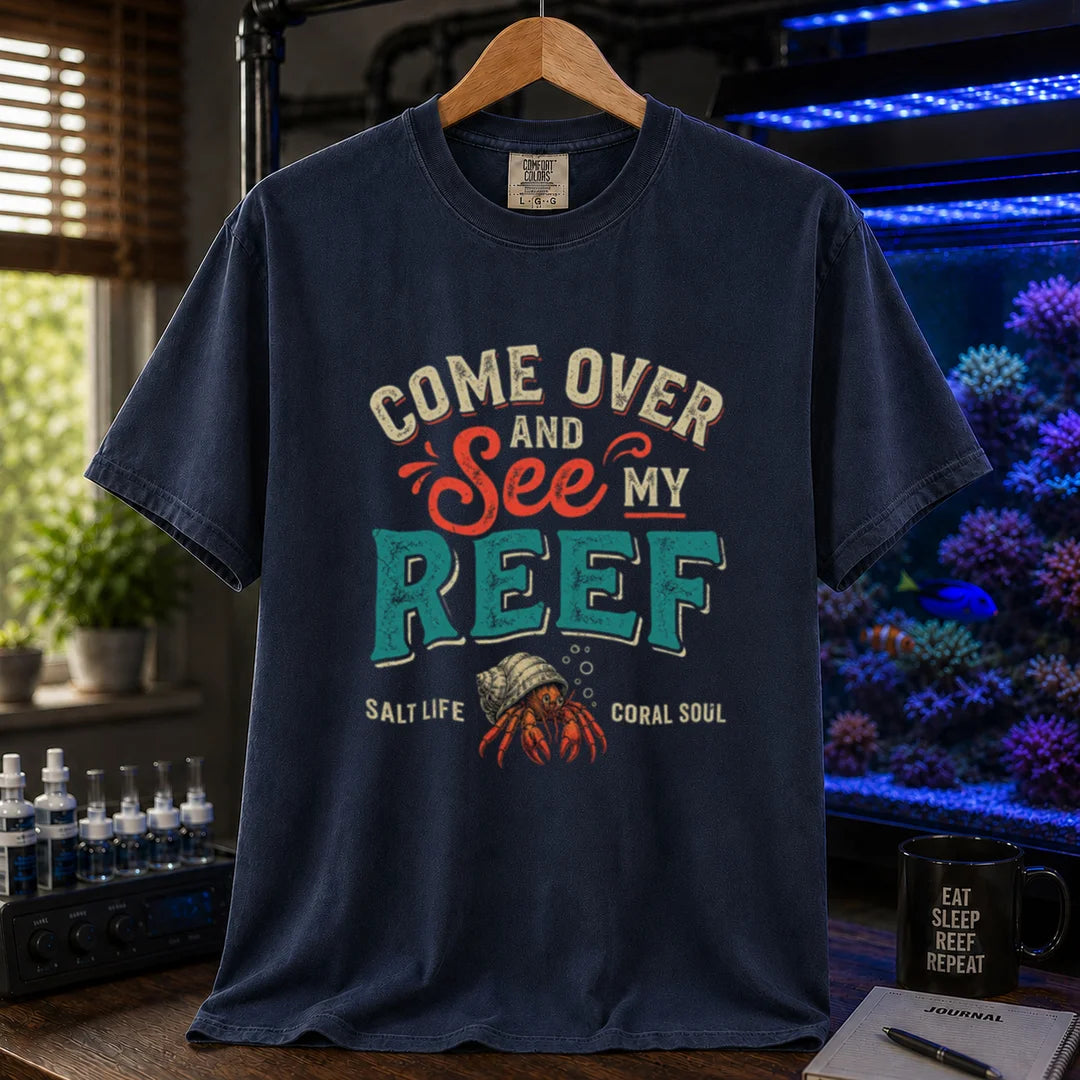 Saltwater aquarium graphic t-shirt featuring distressed retro typography reading Come Over And See My Reef with a hermit crab illustration and footer text, navy crew neck tee