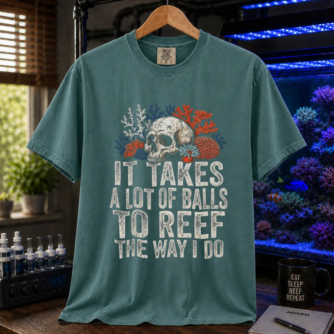 Saltwater aquarium graphic t-shirt featuring distressed white typography reading It Takes A Lot Of Balls To Reef The Way I Do with an illustration of a skull and coral formations, green crew neck tee