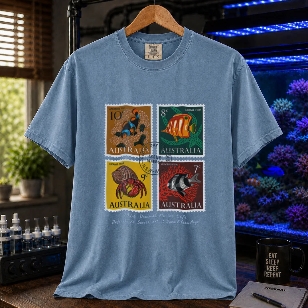 Saltwater aquarium graphic t-shirt featuring a vintage block of four 1966 Australian marine life stamps designed by Dame Eileen Mayo with postmark and script text, blue crew neck tee