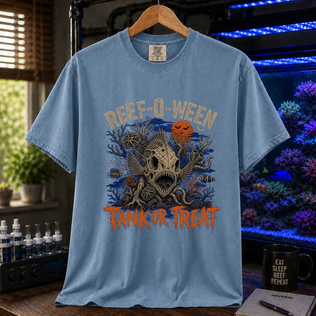 Saltwater aquarium graphic t-shirt design featuring cream arched typography reading Reef-O-Ween and dripping orange text reading Tank Or Treat with a large fish skull skeleton, full moon, bats, and spooky reef corals, blue crew neck tee