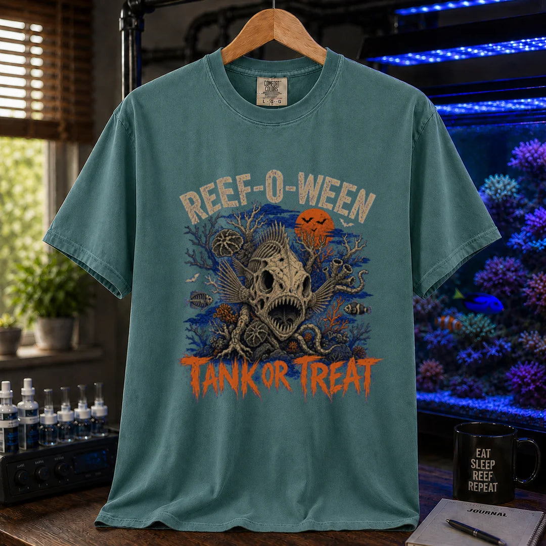 Saltwater aquarium graphic t-shirt design featuring cream arched typography reading Reef-O-Ween and dripping orange text reading Tank Or Treat with a large fish skull skeleton, full moon, bats, and spooky reef corals, green crew neck tee