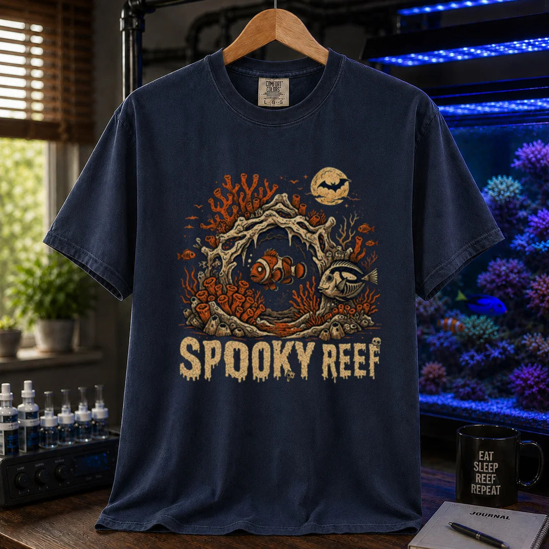 Saltwater aquarium graphic t-shirt design featuring dripping cream typography reading Spooky Reef with a spooky underwater scene featuring skeletal coral, a full moon with a bat, and eerie fish illustrations, navy crew neck tee