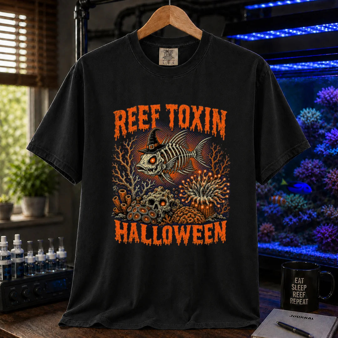 Saltwater aquarium graphic t-shirt design featuring dripping orange typography reading Reef Toxin Halloween with a witch-hat-wearing fish skeleton, glowing zoanthids, a skull in the rocks, and an anemone, black crew neck tee