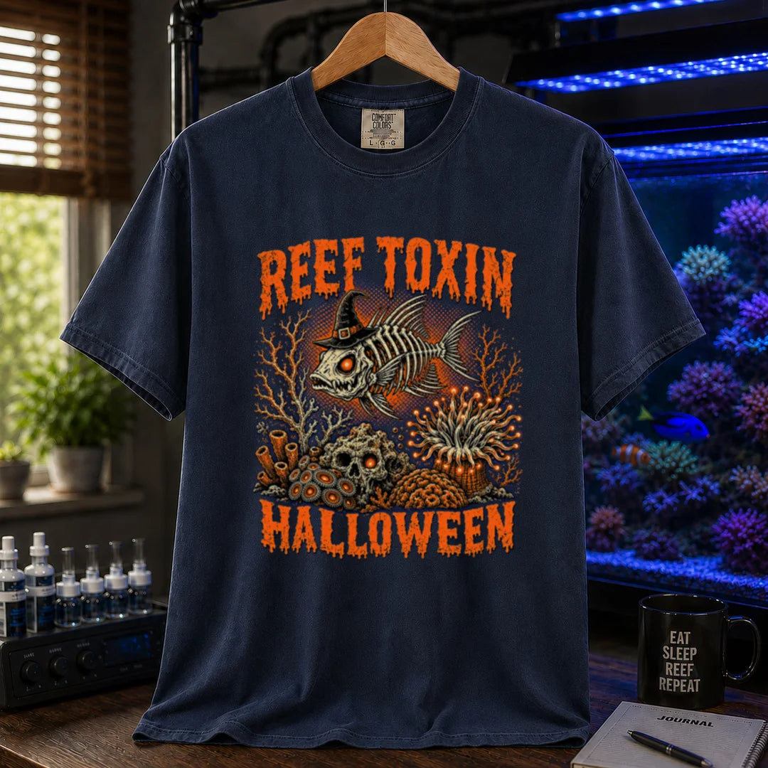 Saltwater aquarium graphic t-shirt design featuring dripping orange typography reading Reef Toxin Halloween with a witch-hat-wearing fish skeleton, glowing zoanthids, a skull in the rocks, and an anemone, navy crew neck tee