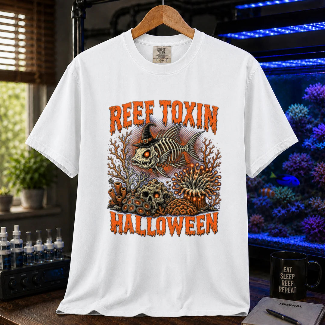 Saltwater aquarium graphic t-shirt design featuring dripping orange typography reading Reef Toxin Halloween with a witch-hat-wearing fish skeleton, glowing zoanthids, a skull in the rocks, and an anemone, white crew neck tee