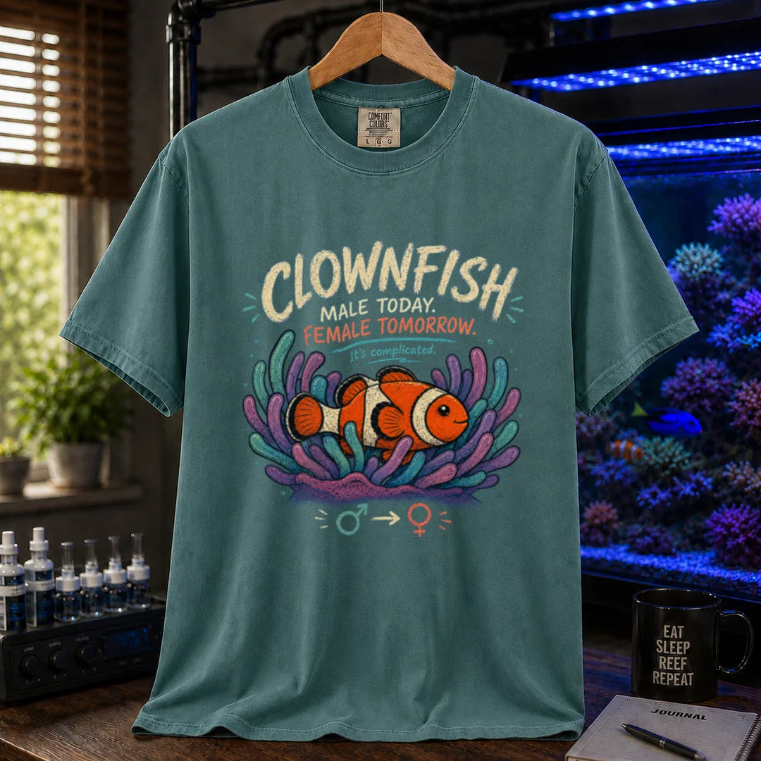 Saltwater aquarium graphic t-shirt design featuring distressed vintage typography reading Clownfish Male Today. Female Tomorrow. It's complicated with a clownfish in an anemone and gender symbols on a green t-shirt