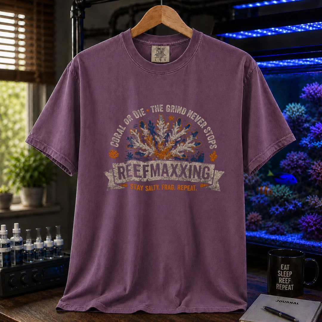 Saltwater aquarium graphic t-shirt design featuring a distressed vintage design reading Reefmaxxxing, Coral Or Die, and Stay Salty. Frag. Repeat. with a central coral graphic on a purple tee