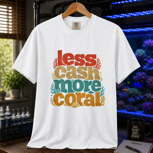 Saltwater aquarium graphic t-shirt design featuring a retro multi-colored stacked typographic layout reading Less Cash More Coral with small coral accents on a white tee