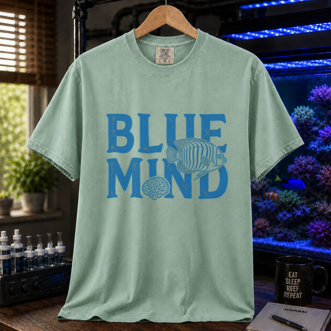 Saltwater aquarium graphic t-shirt design featuring distressed blue typography reading Blue Mind with an angelfish and brain coral illustration on a light green tee