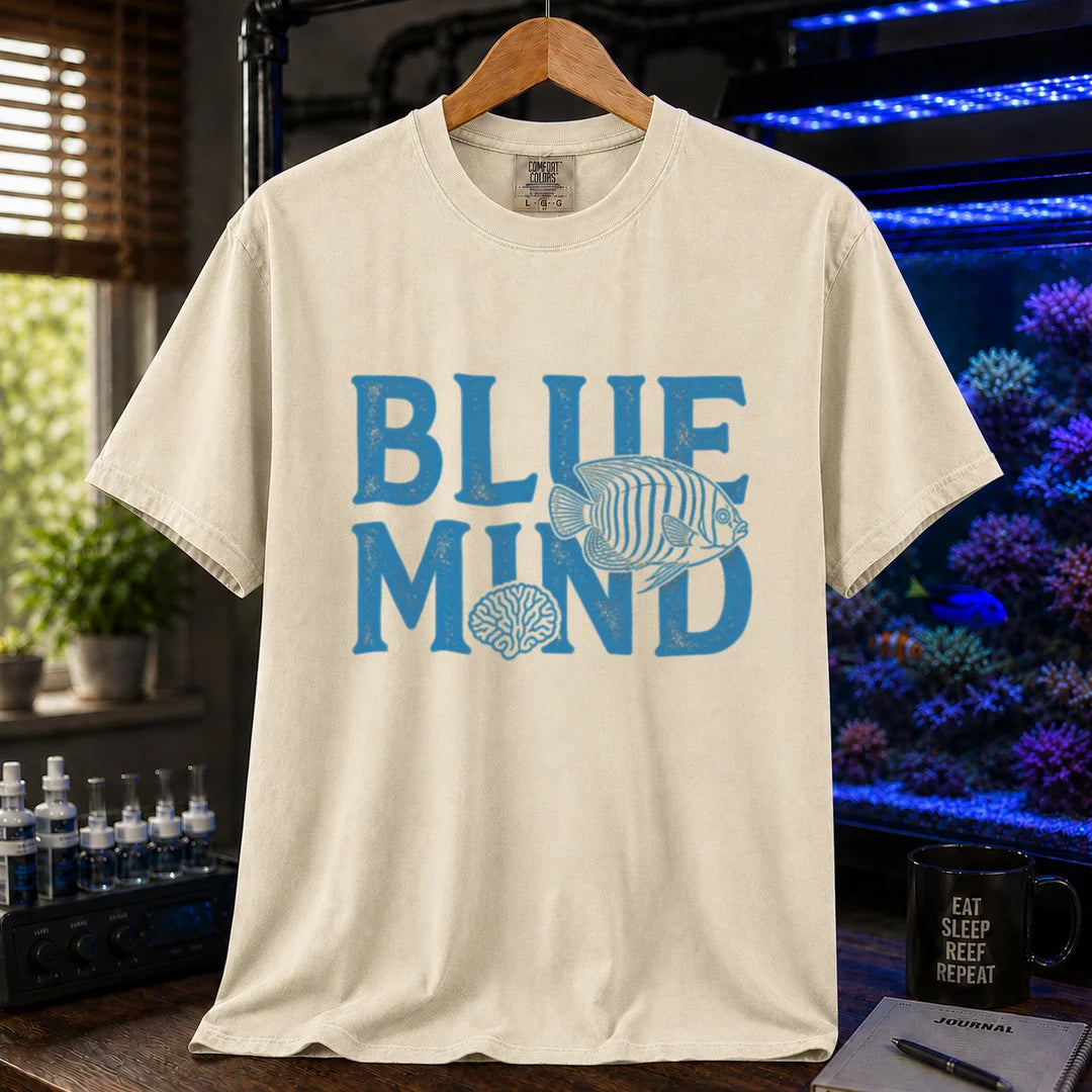Saltwater aquarium graphic t-shirt design featuring distressed blue typography reading Blue Mind with an angelfish and brain coral illustration on a cream, beige, ivory tee
