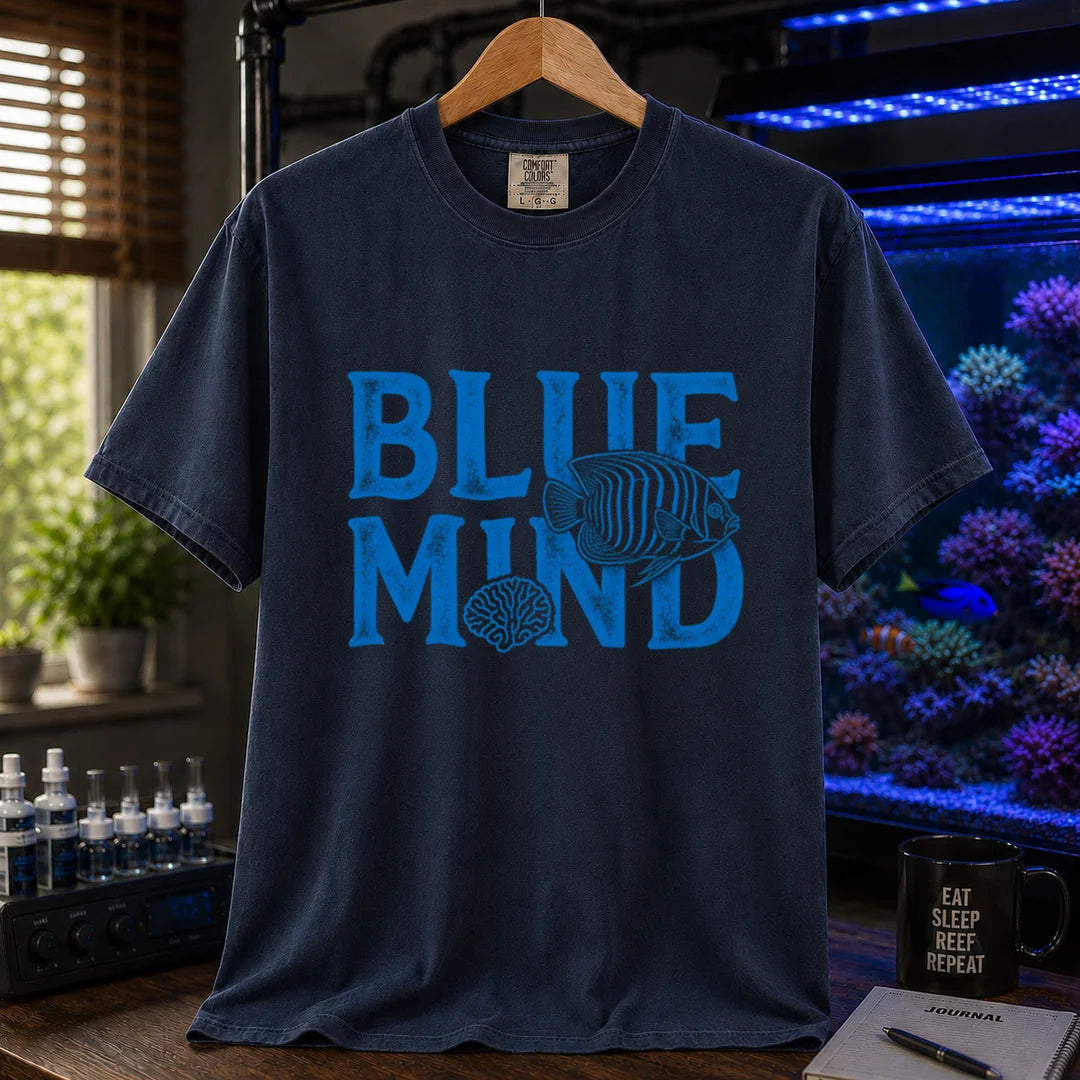 Saltwater aquarium graphic t-shirt design featuring distressed blue typography reading Blue Mind with an angelfish and brain coral illustration on a navy tee