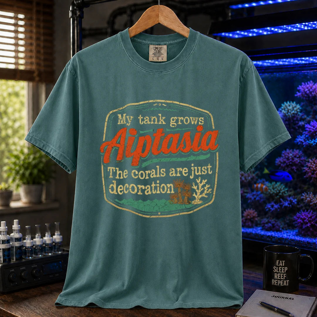 Saltwater aquarium graphic t-shirt design featuring a vintage badge reading My Tank Grows Aiptasia. The corals are just decoration with pest anemone illustrations on a green tee
