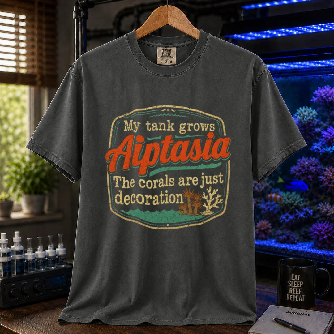 Saltwater aquarium graphic t-shirt design featuring a vintage badge reading My Tank Grows Aiptasia. The corals are just decoration with pest anemone illustrations on a dark grey tee