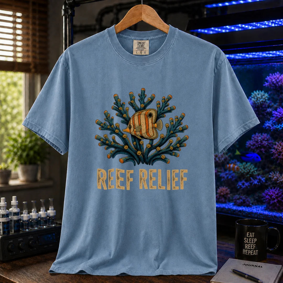 Saltwater aquarium graphic t-shirt design featuring a butterflyfish nestled in a blue coral colony with distressed typography reading Reef Relief on a blue tee