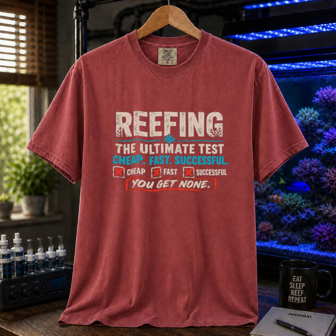 Saltwater aquarium graphic t-shirt design featuring distressed typography reading Reefing The Ultimate Test Cheap. Fast. Successful. with checkbox symbols and the punchline You Get None on a maroon, red tee