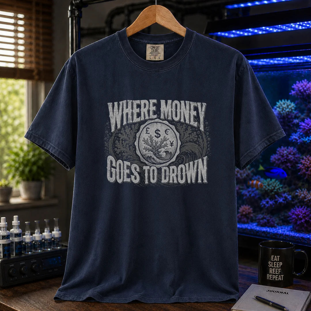 Saltwater aquarium graphic t-shirt design featuring distressed typography reading Where Money Goes To Drown with a central currency symbol and coral emblem on a NAVY tee