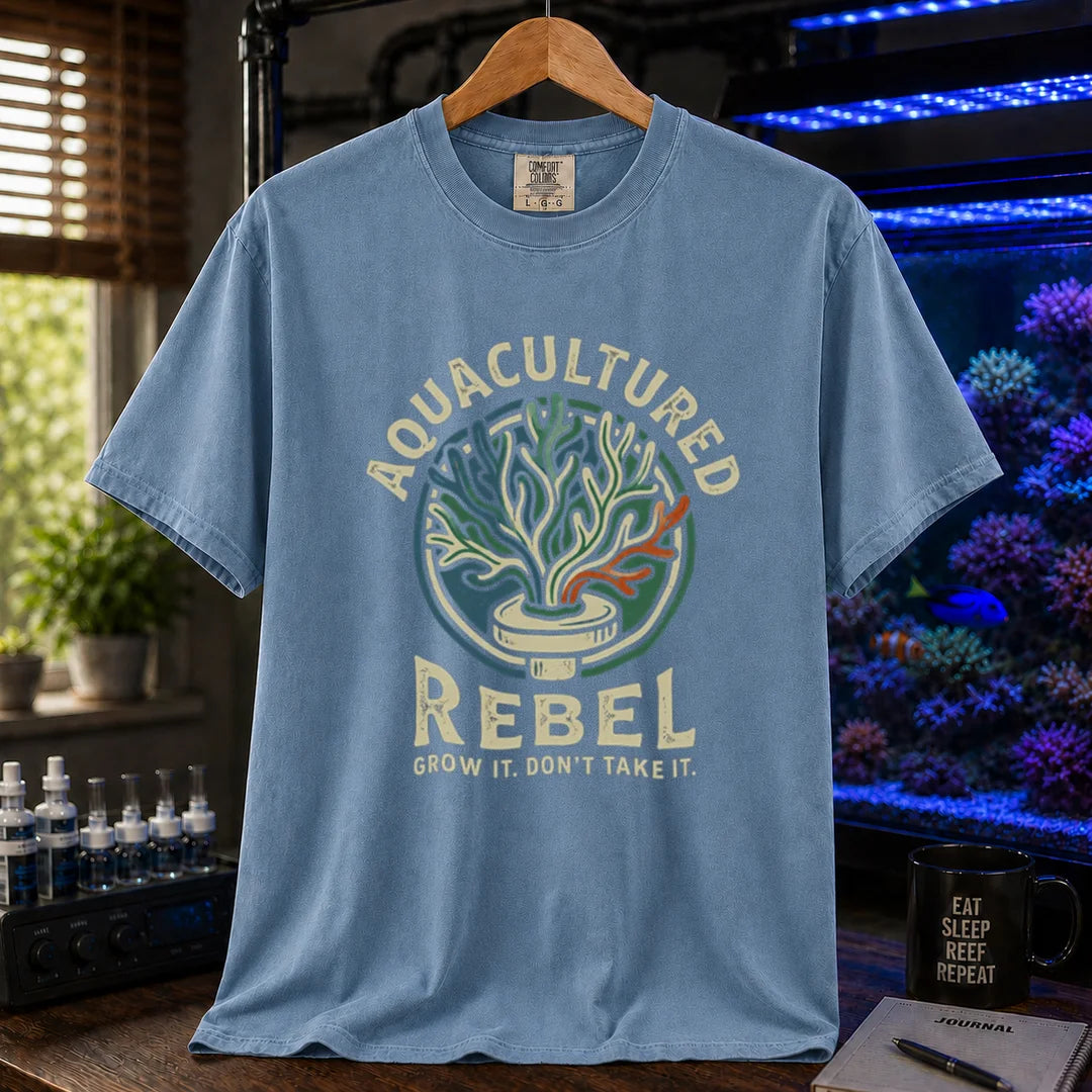 Saltwater aquarium graphic t-shirt design featuring a vintage badge reading Aquacultured Rebel Grow It. Don't Take It. with a coral frag plug illustration on a blue tee
