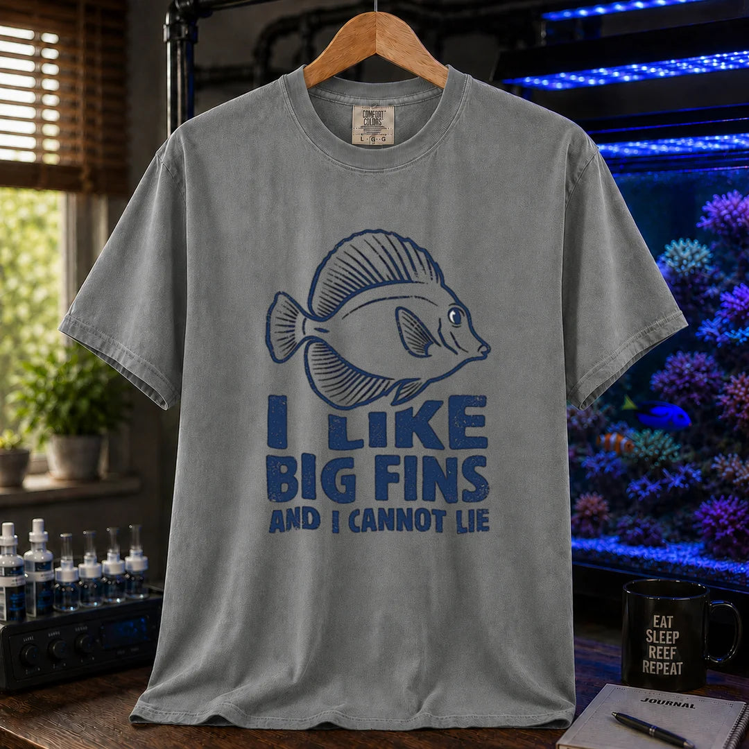 Saltwater aquarium graphic t-shirt design featuring distressed blue typography reading I Like Big Fins And I Cannot Lie with a detailed tang fish illustration on a dark grey tee