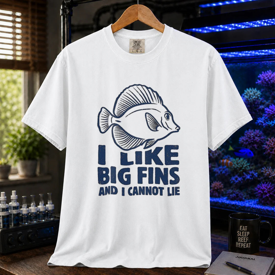 Saltwater aquarium graphic t-shirt design featuring distressed blue typography reading I Like Big Fins And I Cannot Lie with a detailed tang fish illustration on a WHITE tee