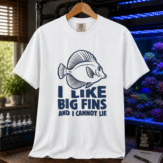 Saltwater aquarium graphic t-shirt design featuring distressed blue typography reading I Like Big Fins And I Cannot Lie with a detailed tang fish illustration on a WHITE tee
