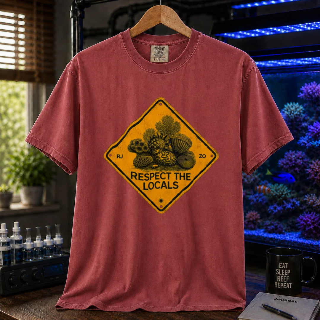 Saltwater aquarium graphic t-shirt design featuring a distressed yellow diamond warning sign reading Respect The Locals with detailed coral and sea life illustrations on a maroon, red tee
