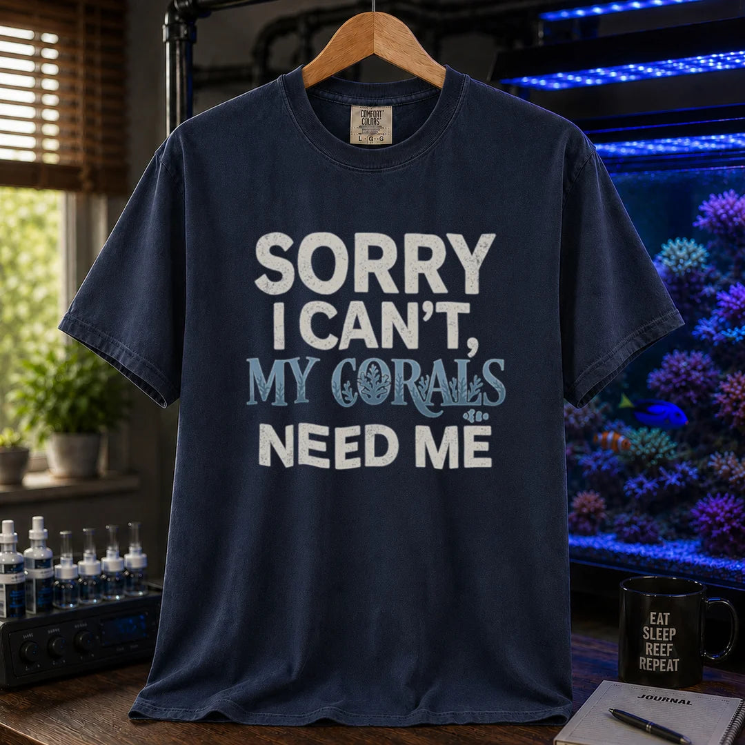 Saltwater aquarium graphic t-shirt design featuring distressed typography reading Sorry I Can't, My Corals Need Me with integrated coral silhouettes on a navy tee